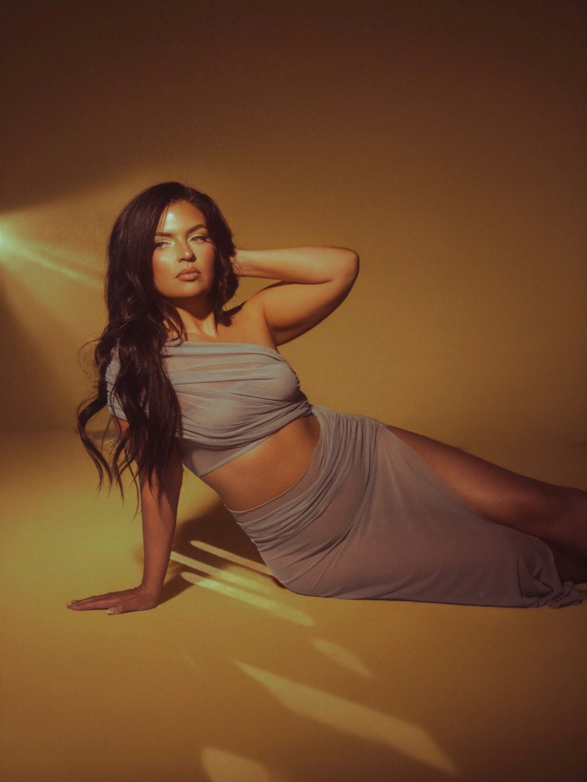 Golden-lit studio portrait of a woman in a taupe two-piece set